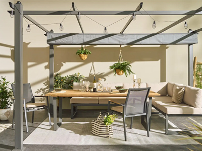 Terrasse mit Pergola, Esstisch, Stühlen, Sofagarnitur, Hängepflanzen und Lichterketten